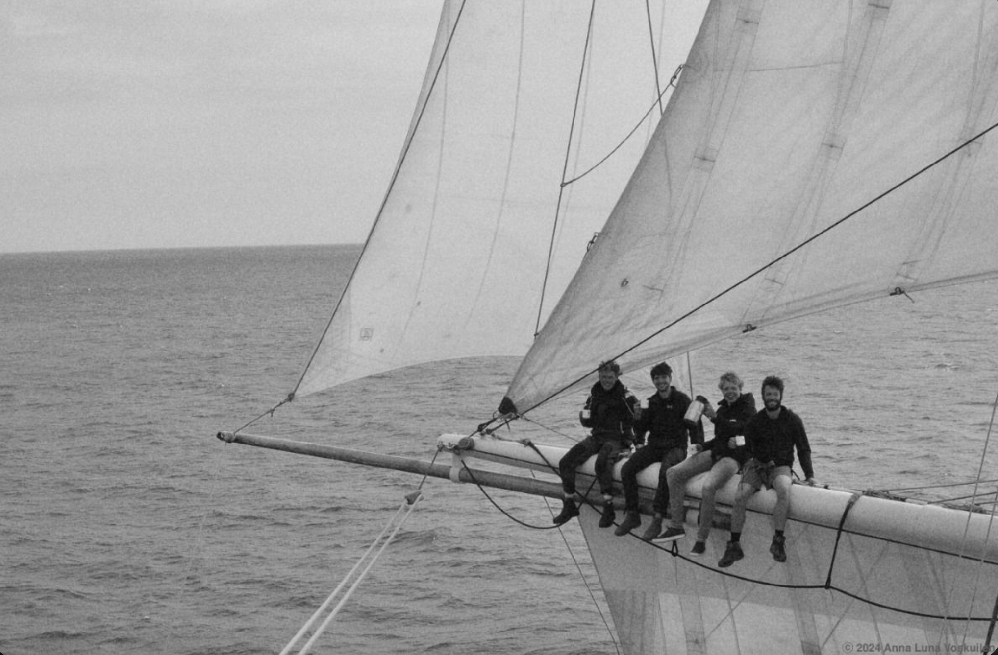 Friends going sailing and sitting on the bow of their sailboat.